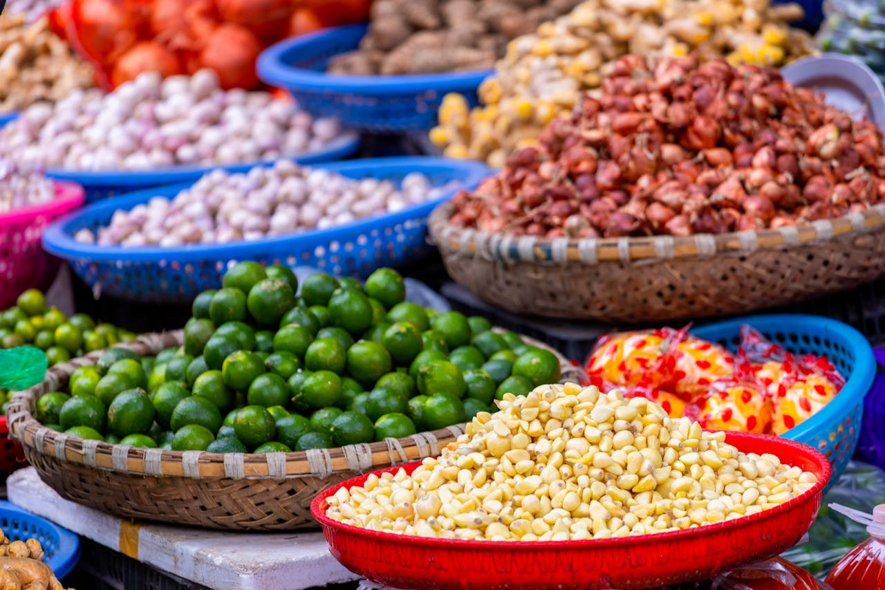 brand-01 Vibrant display of fresh produce at a market in Hanoi, Vietnam, showcasing limes, garlic, and more.